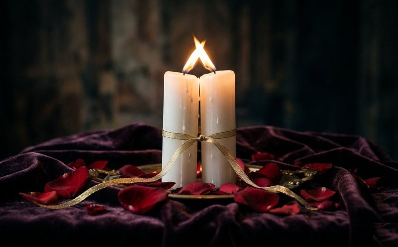 Dos velas blancas y rosas frente a un altar de armonización de pareja